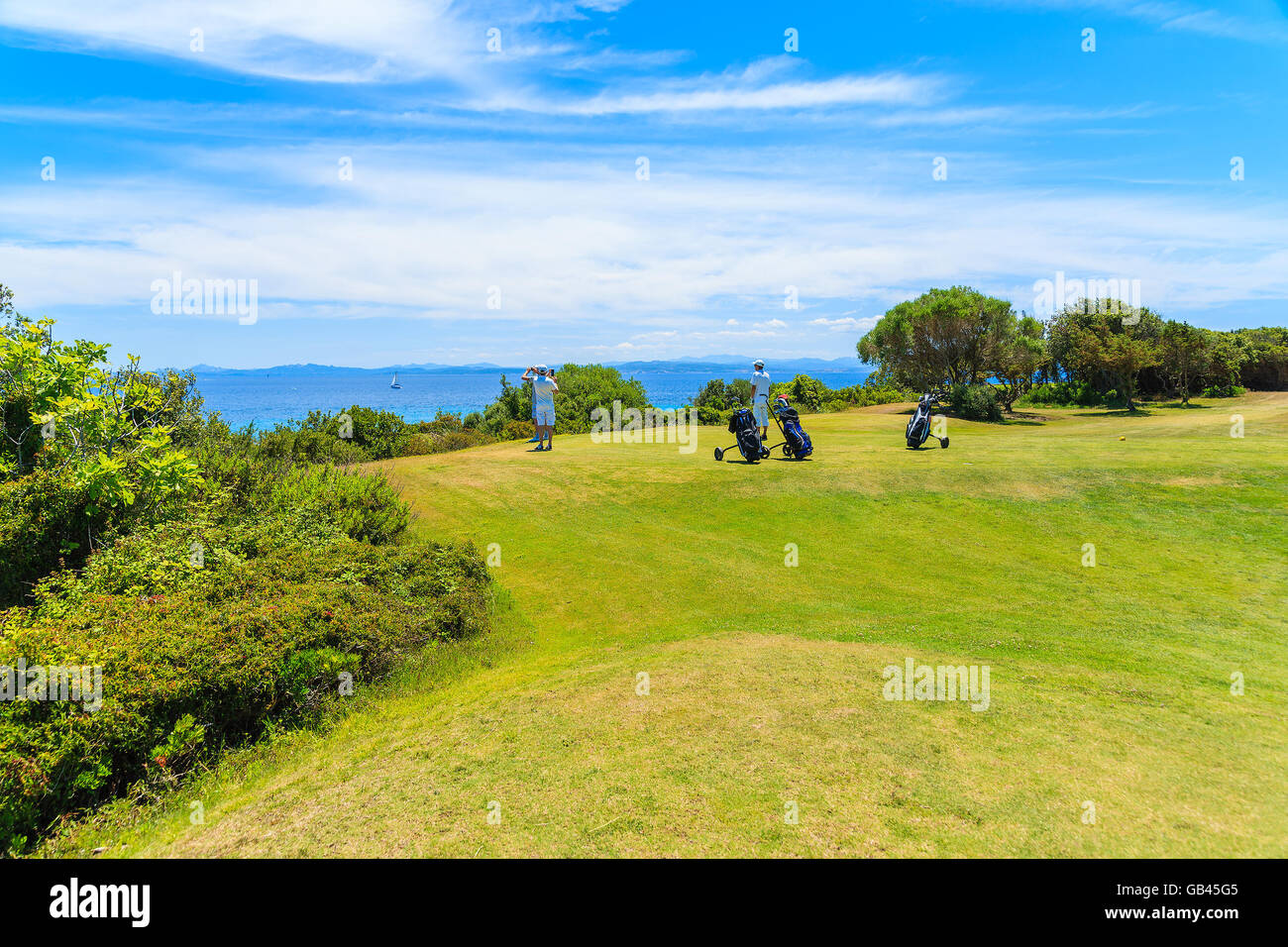 Los golfistas no identificados en la zona de hierba verde del campo de golf mirando al hermoso mar, la isla de Córcega, Francia Foto de stock
