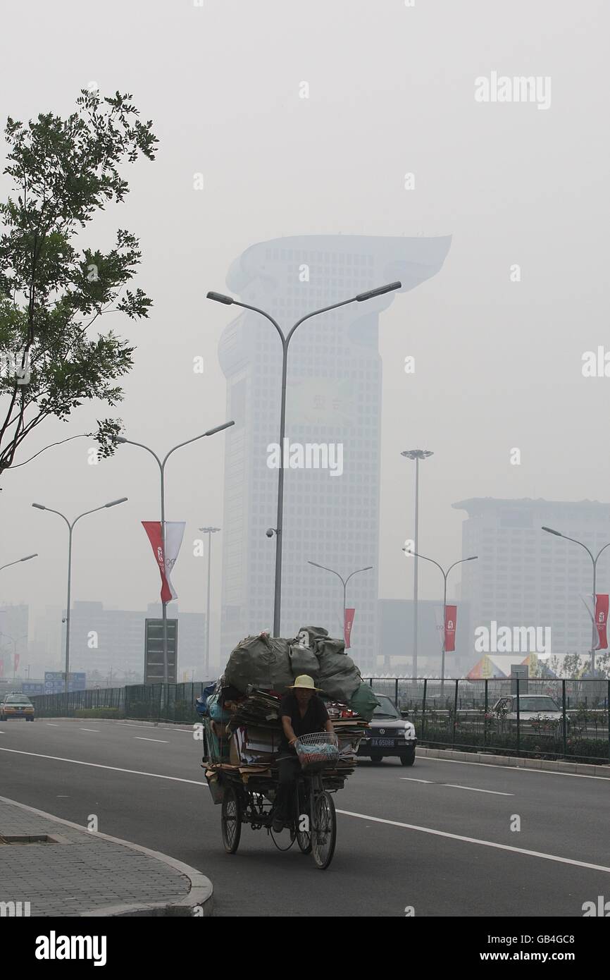Un ciudadano chino transporta una carga pesada en un triciclo a través del smog en Beijing, China. Foto de stock