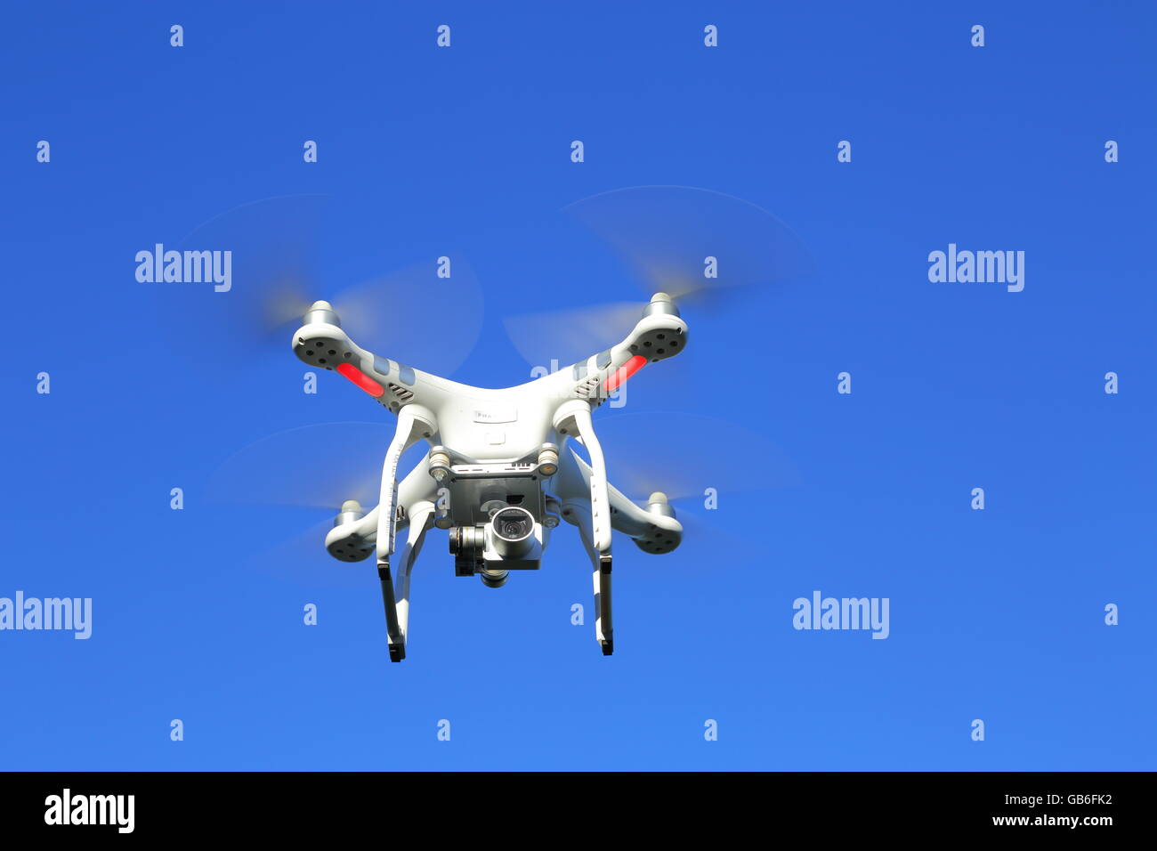 Un avión teledirigido, o UAV, o quadcopter, en vuelo bajo un intenso cielo azul. Foto de stock