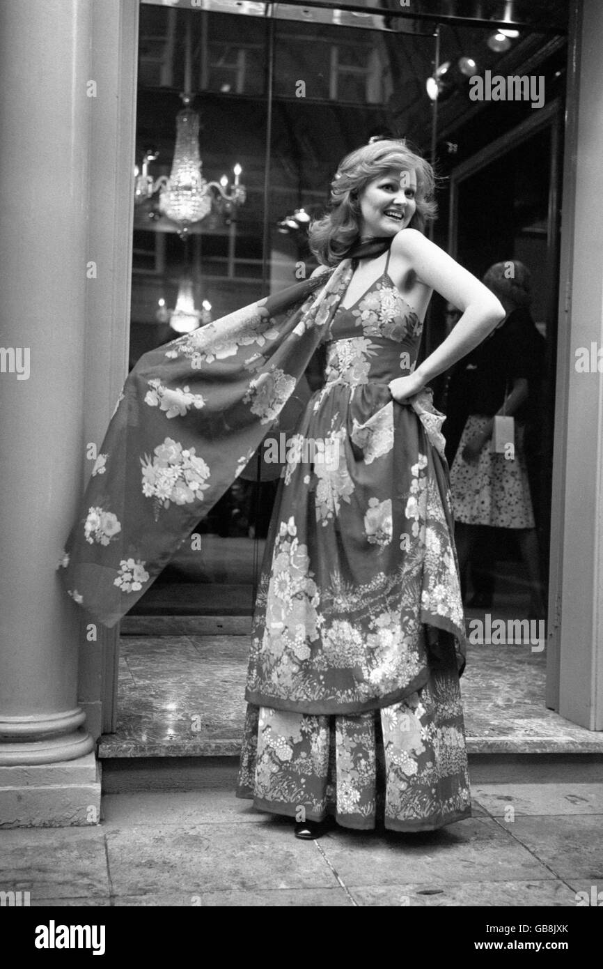 Moda - Dior-London Summer Collection - 1973. Vestido de noche en voile de algodón estampado floral fino con falda de dos niveles y una larga estola mostrada por Sarah. Foto de stock