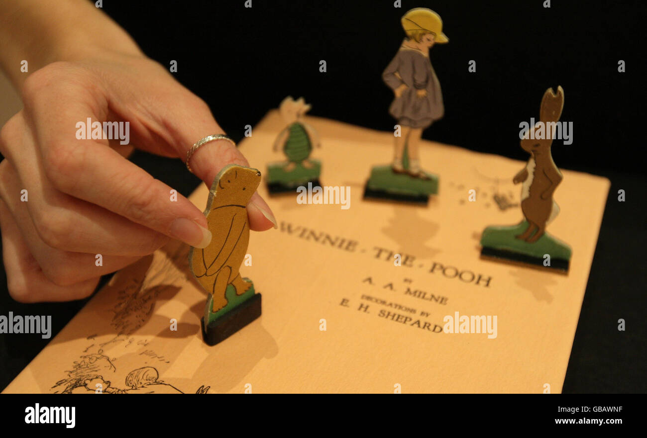 Un miembro del personal de la casa de subastas Sotheby's ajusta una muestra de figuras de 'Pooh va a visitar' un conjunto de productos Winnie the Pooh temprano, parte de una colección de ilustraciones y libros de Winnie the Pooh que se venderá en subasta el 17th de diciembre. Foto de stock