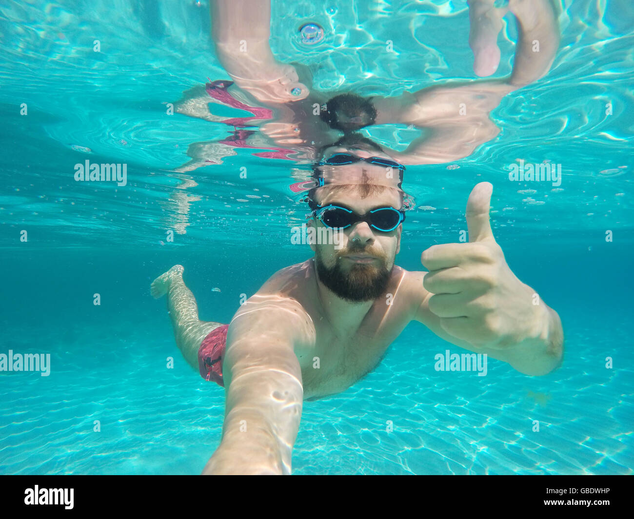 Barba Joven Hombre con gafas de buceo en un agua limpia azul Foto de stock