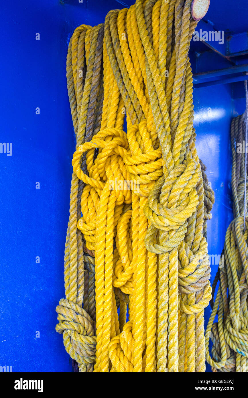 Amarillo cuerda colgando junto a un tablero azul Foto de stock
