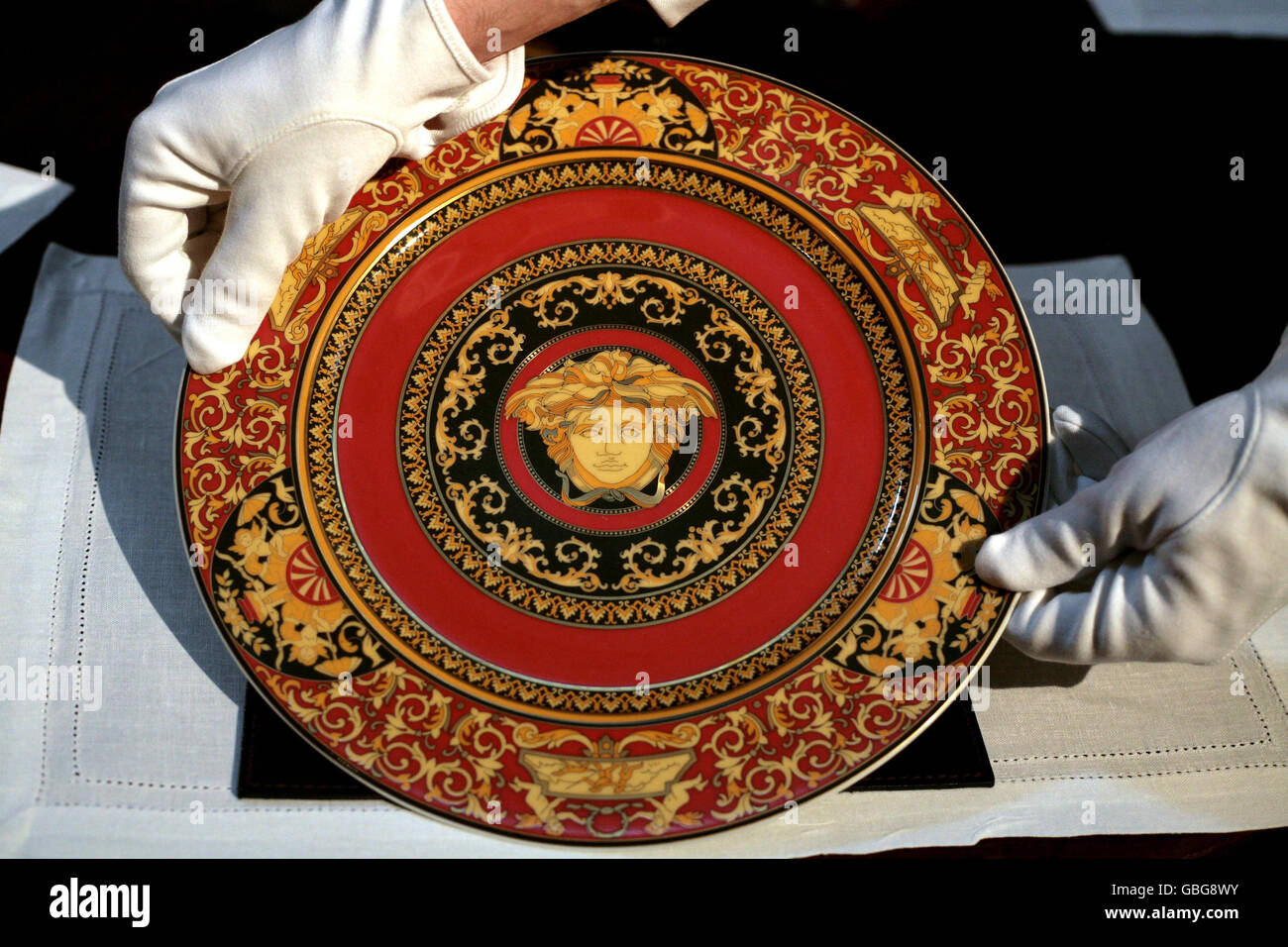Un empleado de Sotheby's sostiene un plato con el símbolo de Versace, una  de una colección propiedad de Gianni Versace, artículos de su Villa del  Lago Como que irá debajo del martillo