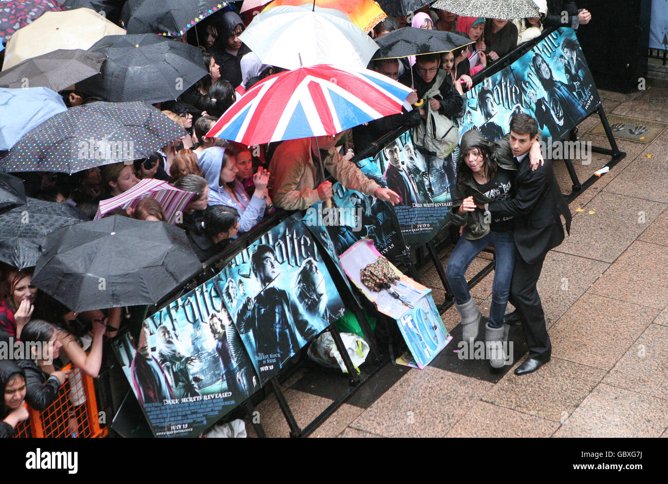 Un fan es removido de la multitud durante la lluvia intensa en el estreno mundial de Harry Potter y el príncipe de la media sangre en el Odeon Leicester Square, Londres. Foto de stock