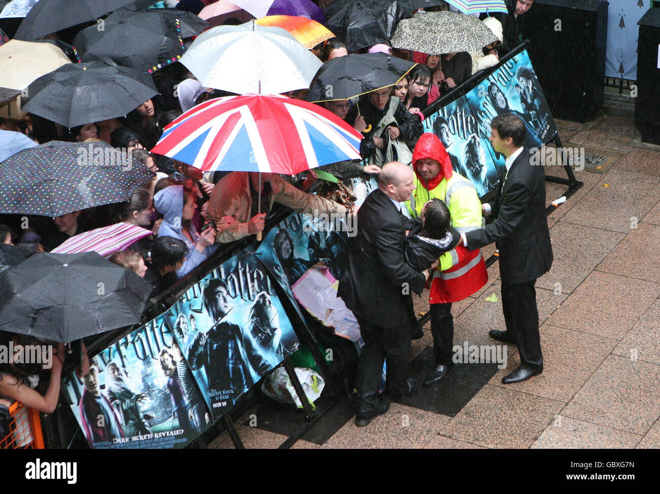 Un fan es removido de la multitud durante la lluvia intensa en el estreno mundial de Harry Potter y el príncipe de la media sangre en el Odeon Leicester Square, Londres. Foto de stock