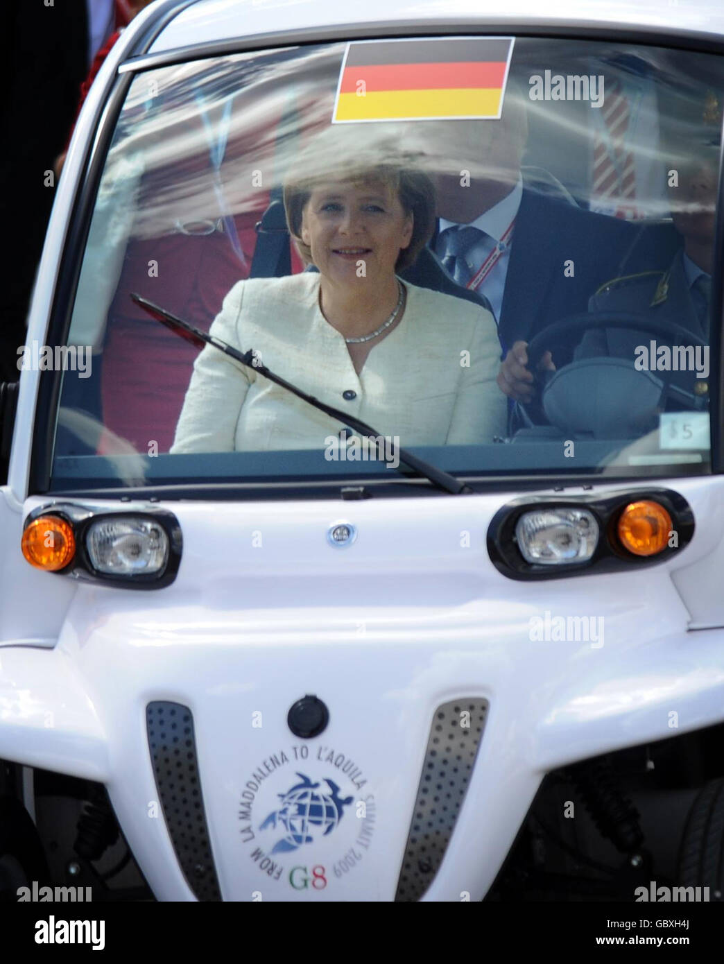 La canciller alemana Angela Merkel llega en buggy de golf para asistir al Foro de las Grandes Economías con otros G8 líderes en la Cumbre de G8 en L'Aquila, Italia. Foto de stock
