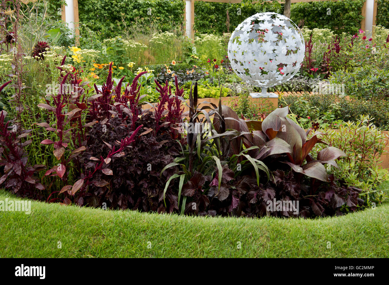 Un diseño en espiral de plantas rojo profundo en el Witan Show Garden el crecimiento mundial en el Hampton Court Palace Flower Show 2016 Foto de stock