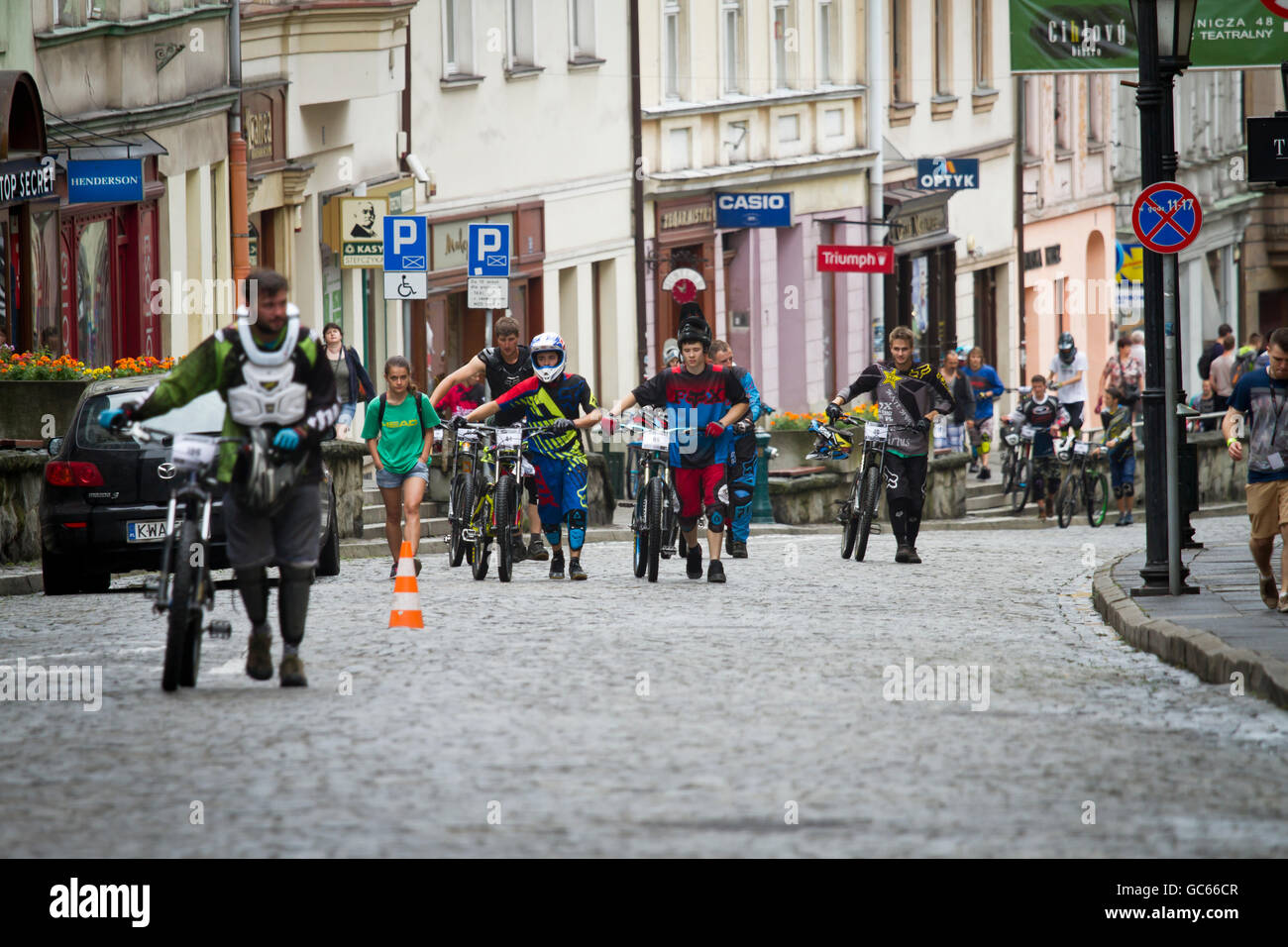 Los ciclistas caminar sus bicicletas de una calle empinada, después de ciudad carrera cuesta abajo. Cieszyn. Polonia. Foto de stock