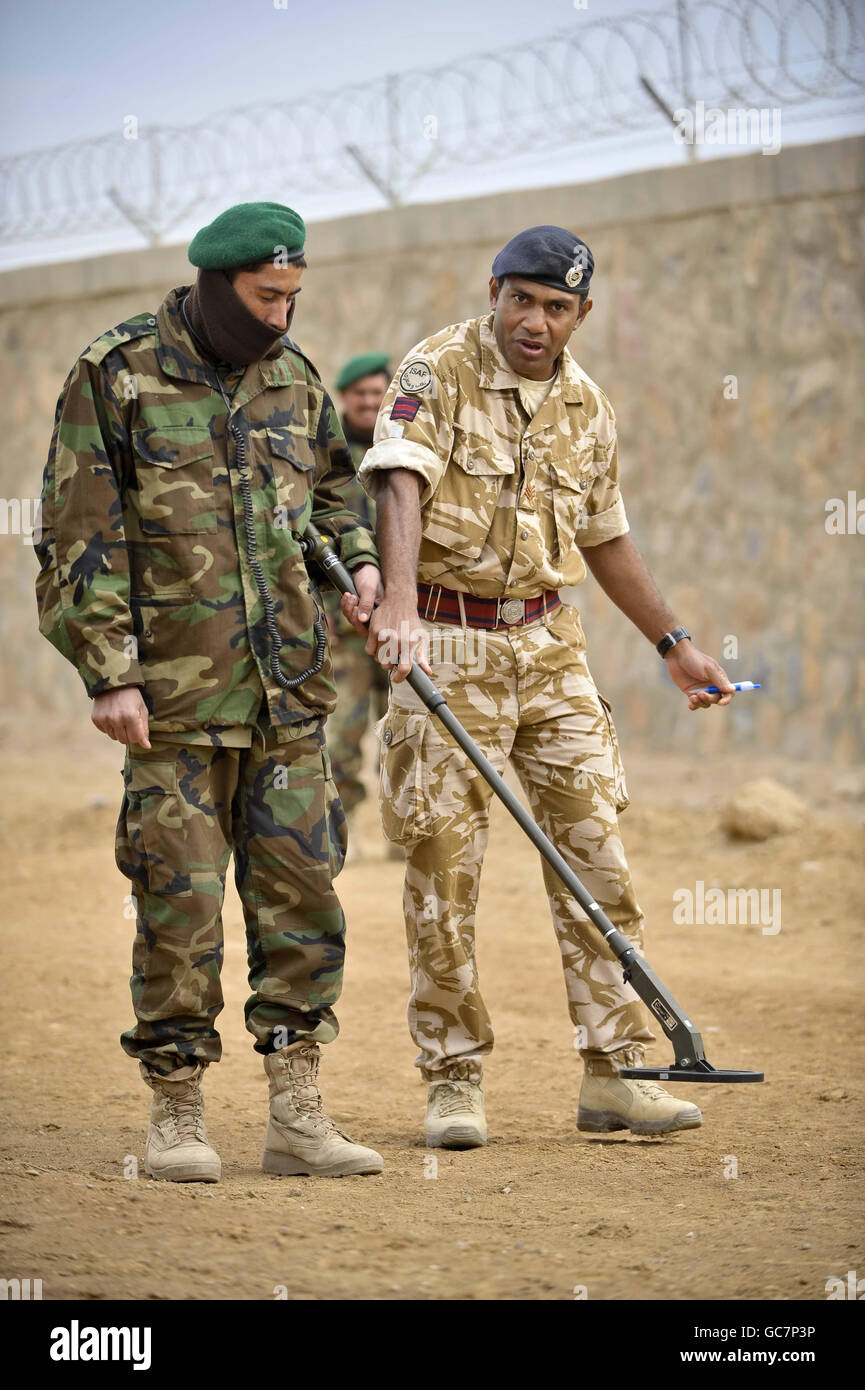 Los soldados e intérpretes británicos enseñan a los soldados del Ejército Nacional afgano técnicas de búsqueda de dispositivos explosivos improvisados (IED) utilizando detectores electrónicos portátiles en el campamento Shurabak, provincia de Helmand, Afganistán, como parte del entrenamiento en curso de las fuerzas de la coalición. Foto de stock