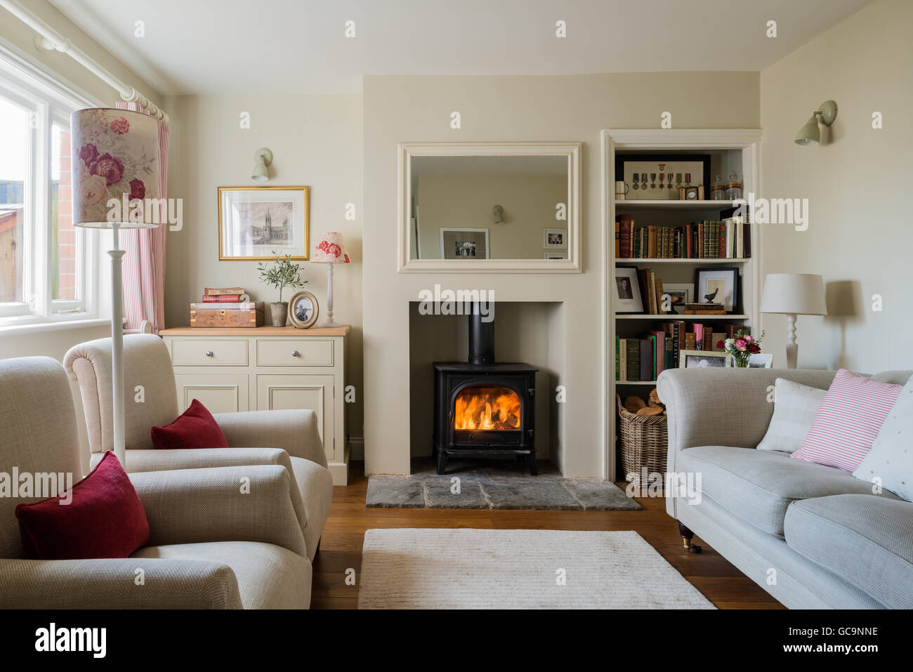Casa rural acogedora sala de estar con estufa de leña y ropa de cama sofá tapizado Foto de stock