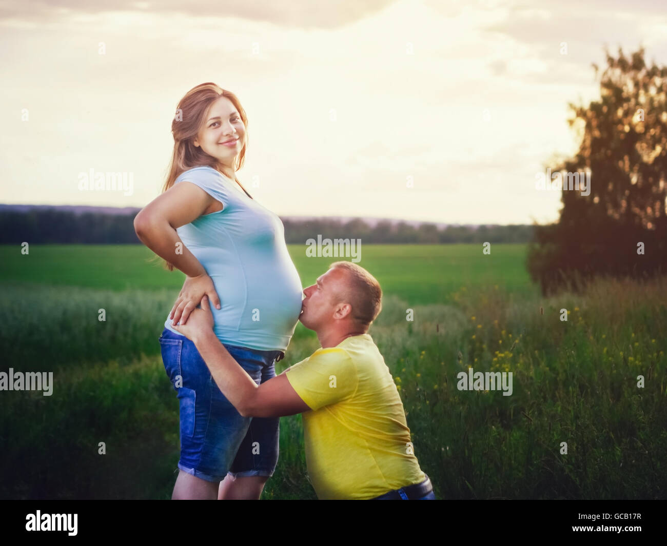 Hombre bese embarazada vientre de su esposa en el exterior Foto de stock