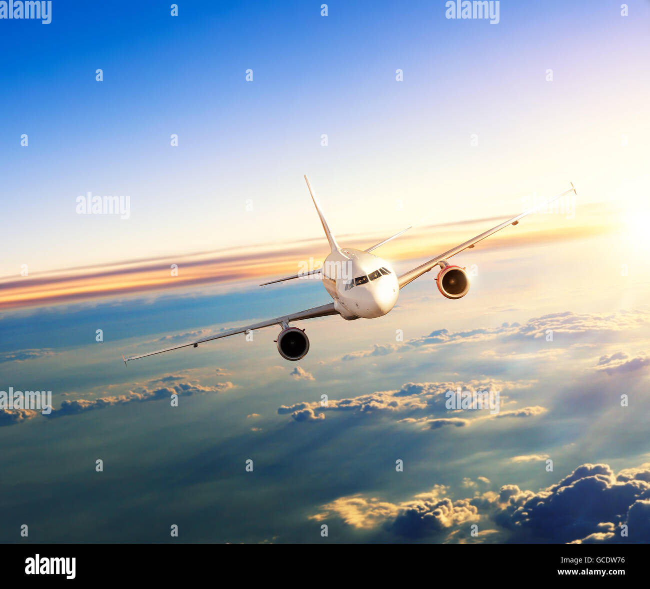 El avión comercial volando por encima de las nubes en la dramática luz del atardecer Foto de stock