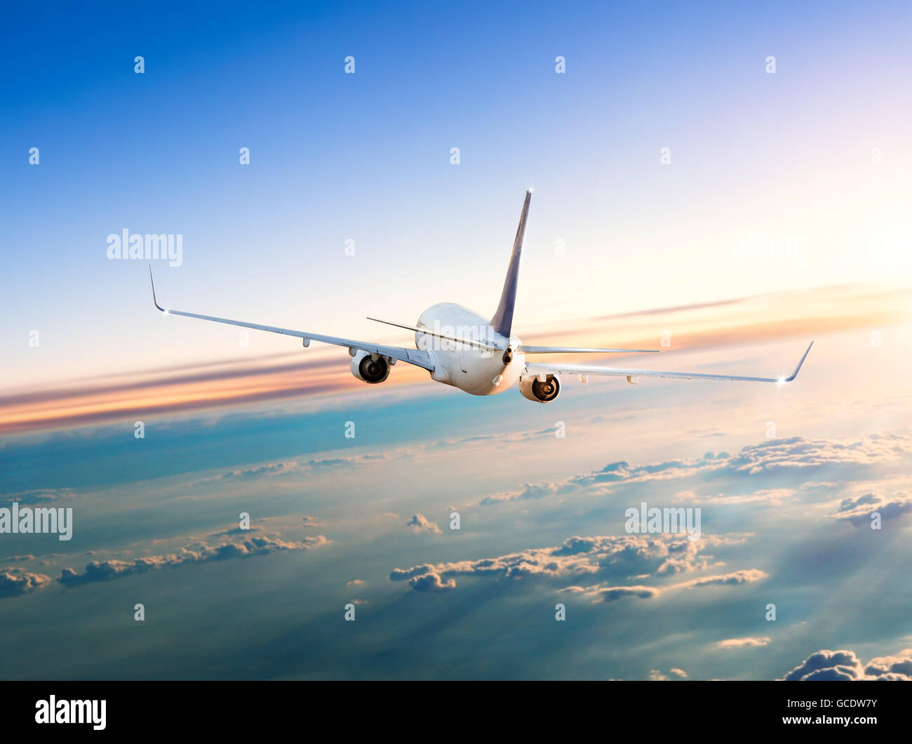 El avión comercial volando por encima de las nubes en la dramática luz del atardecer Foto de stock