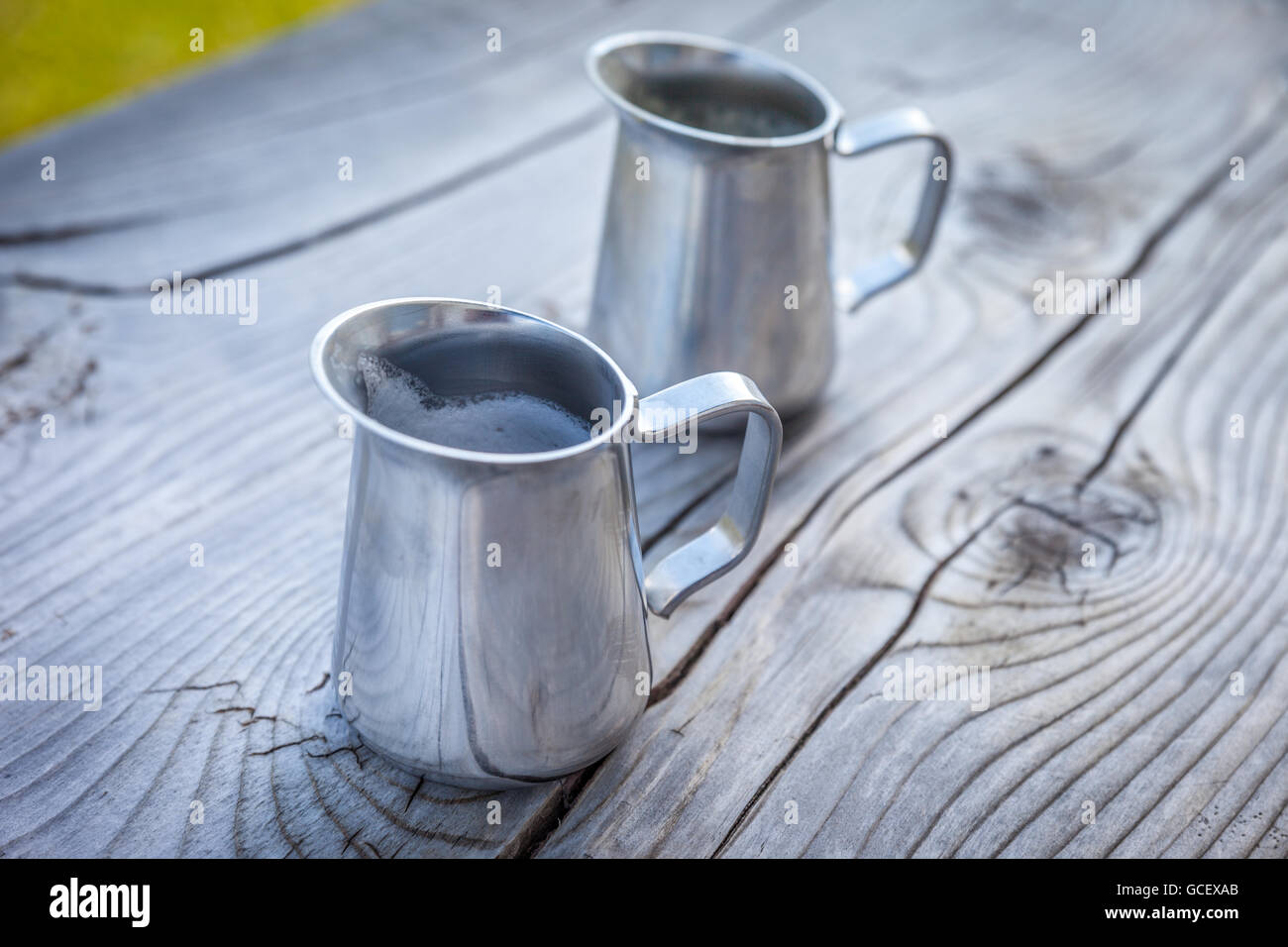 Pequeña jarra de leche sobre la mesa de madera antigua en una granja de montaña en el Tirol del Sur, Italia Foto de stock