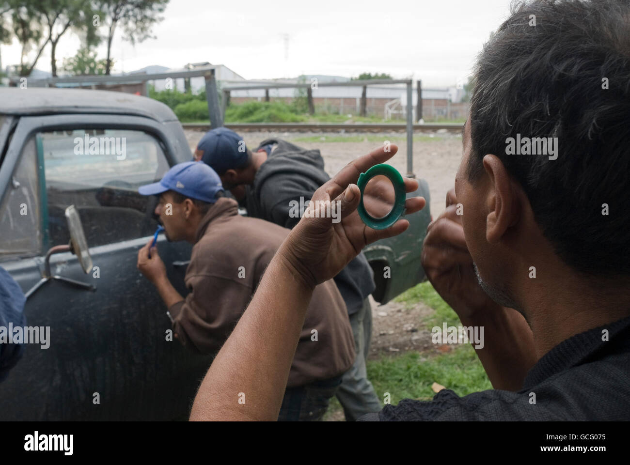 Un grupo de migrantes de Honduras y Nicaragua hace uso de un automóvil abandonado a afeitarse y lavarse antes de continuar hacia el norte. Foto de stock