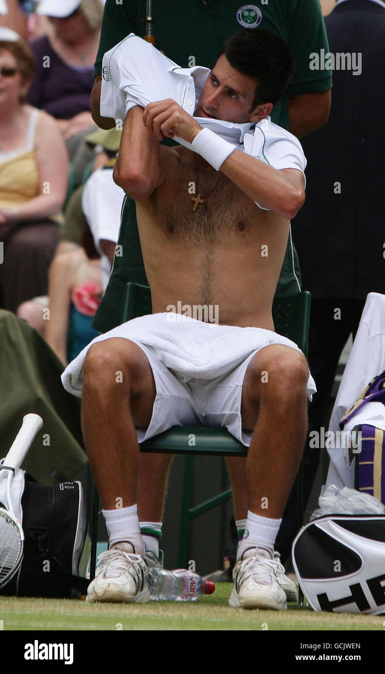 Novak Djokovic de Serbia cambia su camiseta en su partido contra Tomas Berdych de la República Checa durante el día once del Campeonato de Wimbledon 2010 en el All England Lawn Tennis Club, Wimbledon. Foto de stock