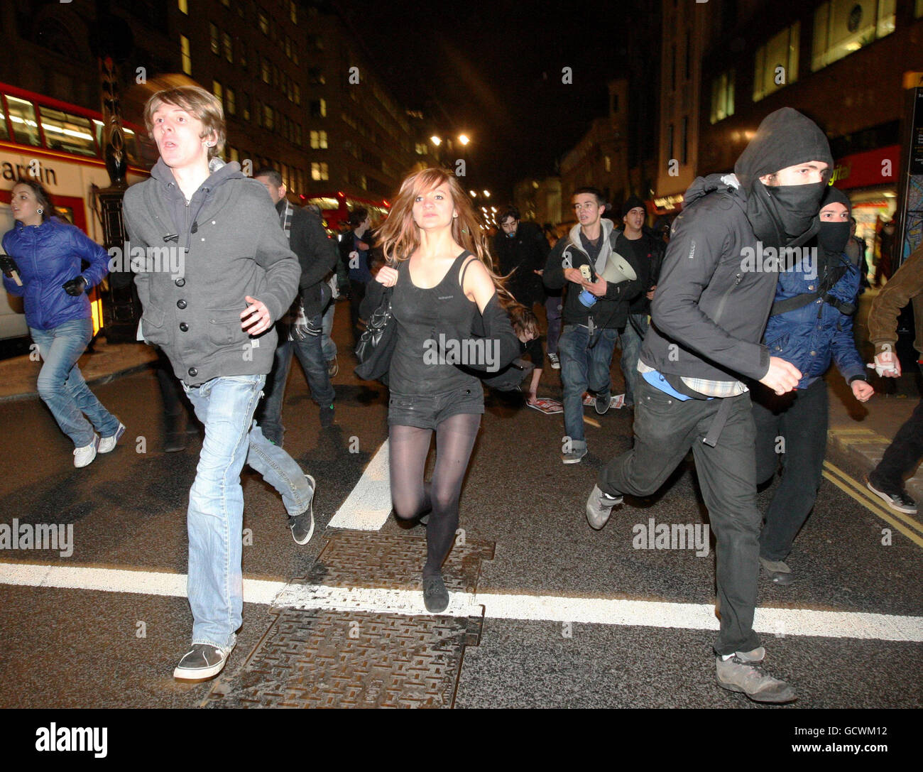 La gente corre a lo largo del Strand, en el centro de Londres, después de las protestas en Westminster contra un aumento en las tasas de matrícula universitaria. Foto de stock