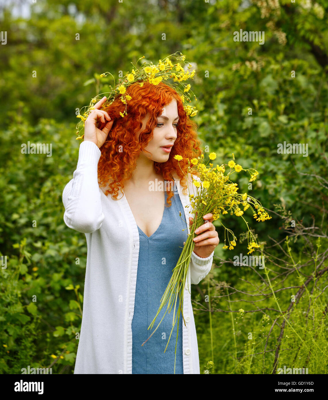 Pelo rojo atractivo joven mujer teje una guirnalda de flores silvestres.  Chica hippie. La unidad con la naturaleza Fotografía de stock - Alamy