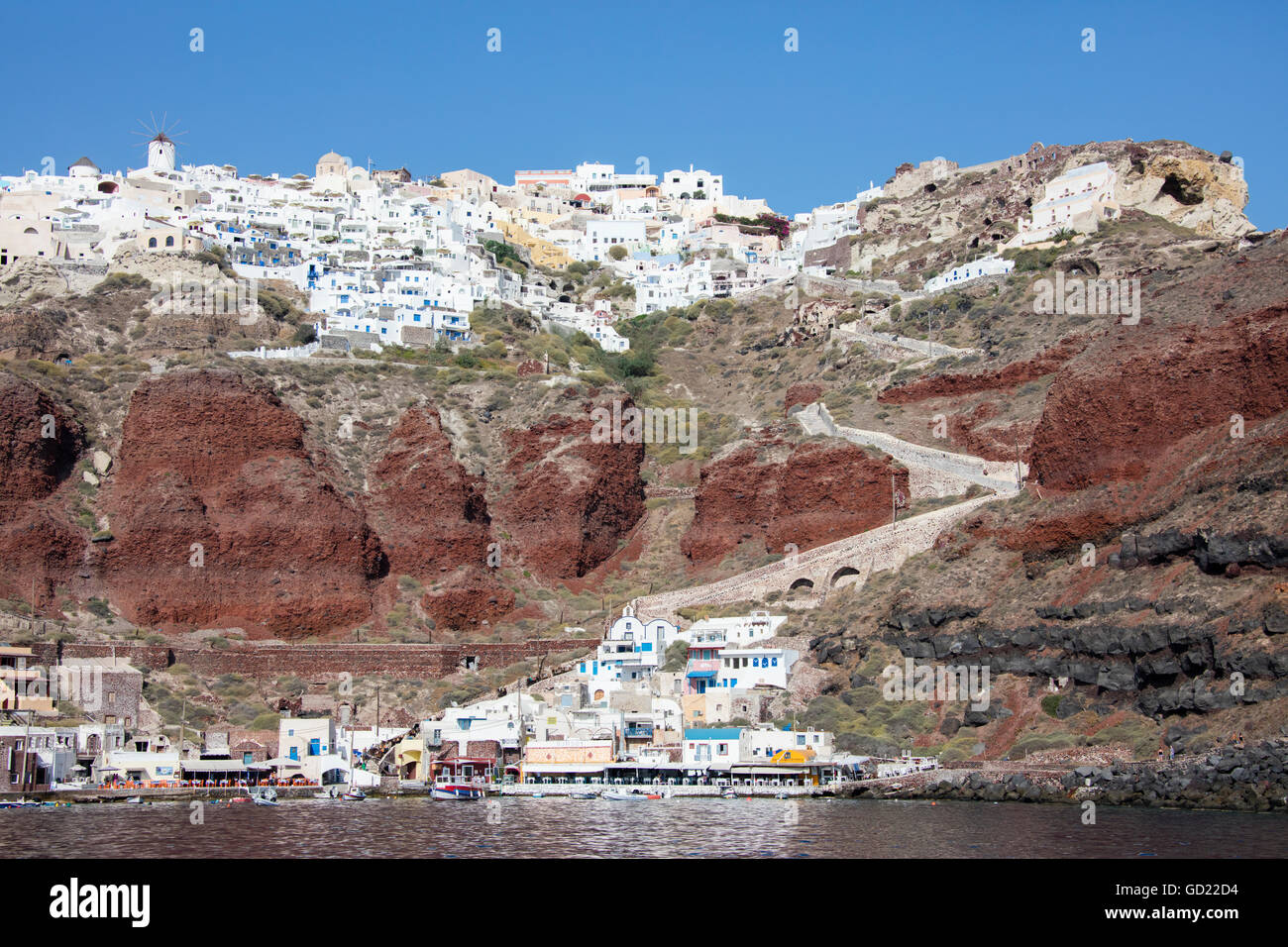 Típico pueblo griego encaramado sobre roca volcánica con casas blancas y azules y los molinos de viento, Santorini, Cícladas, Grecia Foto de stock