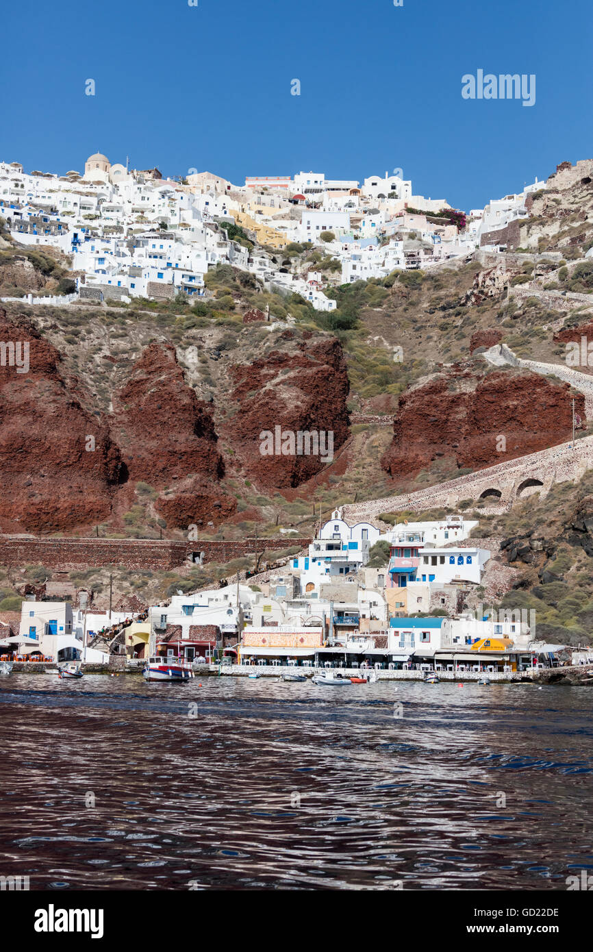 Típico pueblo griego encaramado sobre roca volcánica con casas blancas y azules y los molinos de viento, Santorini, Cícladas, Grecia Foto de stock