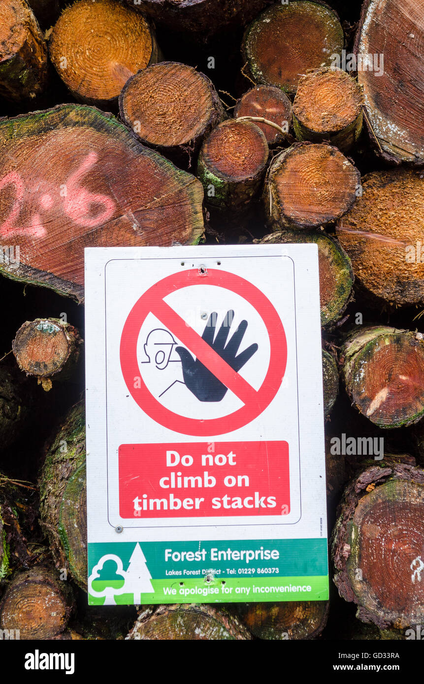 Un signo de advertencia sobre una pila de troncos en un bosque en alturas Claife administrado cerca de Bowness-on-Windermere, en el Lake District National Park, Cumbria, Inglaterra. Foto de stock