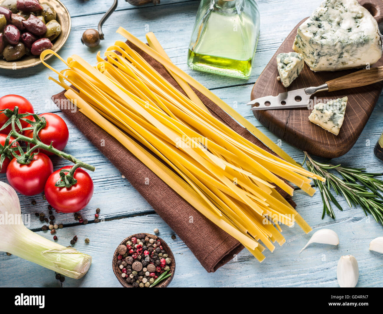 Pasta ingredientes. Tomates Cherry, spaghetti pasta, romero y especias sobre la mesa de madera. Foto de stock