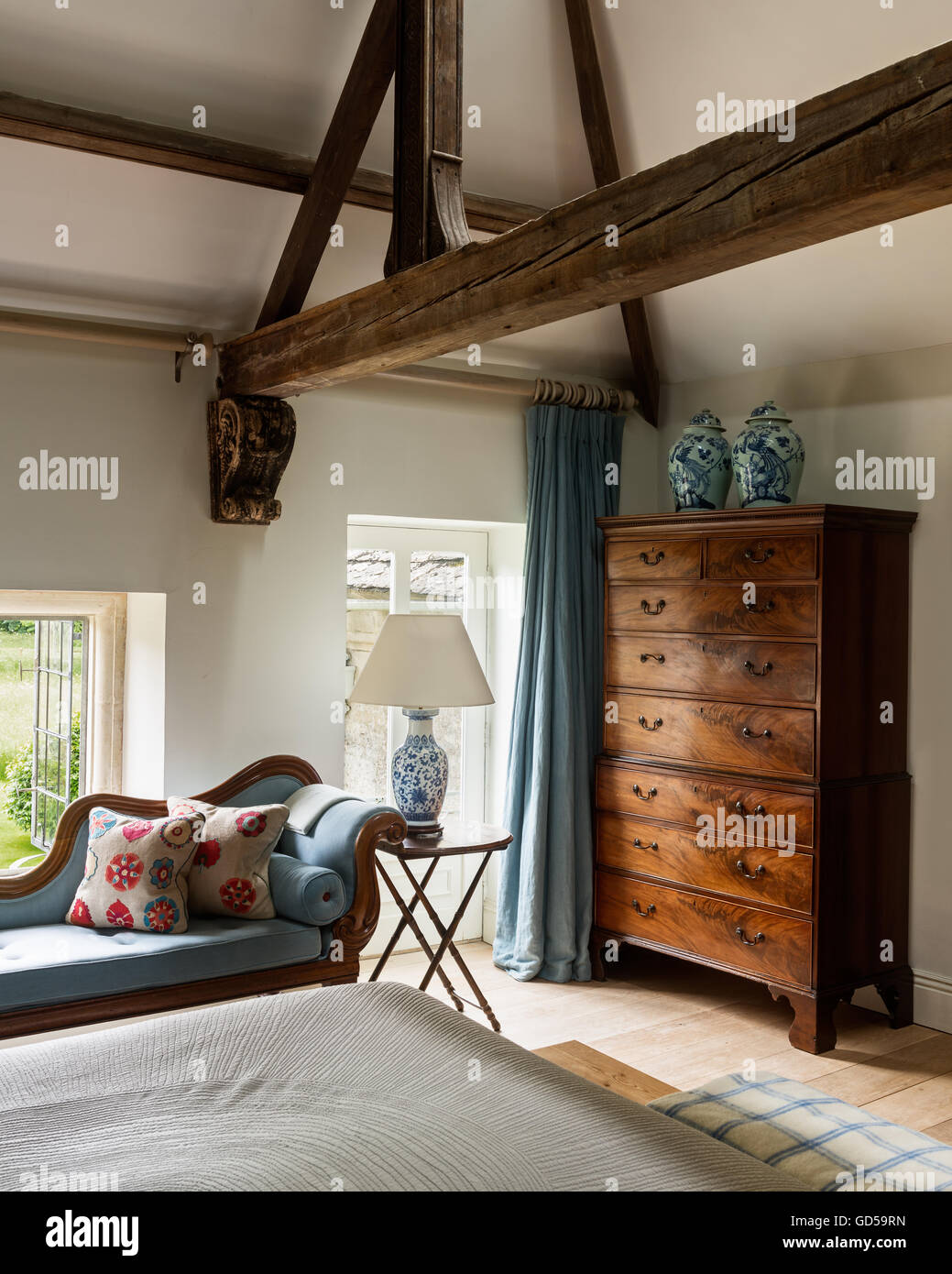 Seguro chaise longue azul en el dormitorio con muebles antiguos de altos  techos con vigas de madera y de pecho Fotografía de stock - Alamy