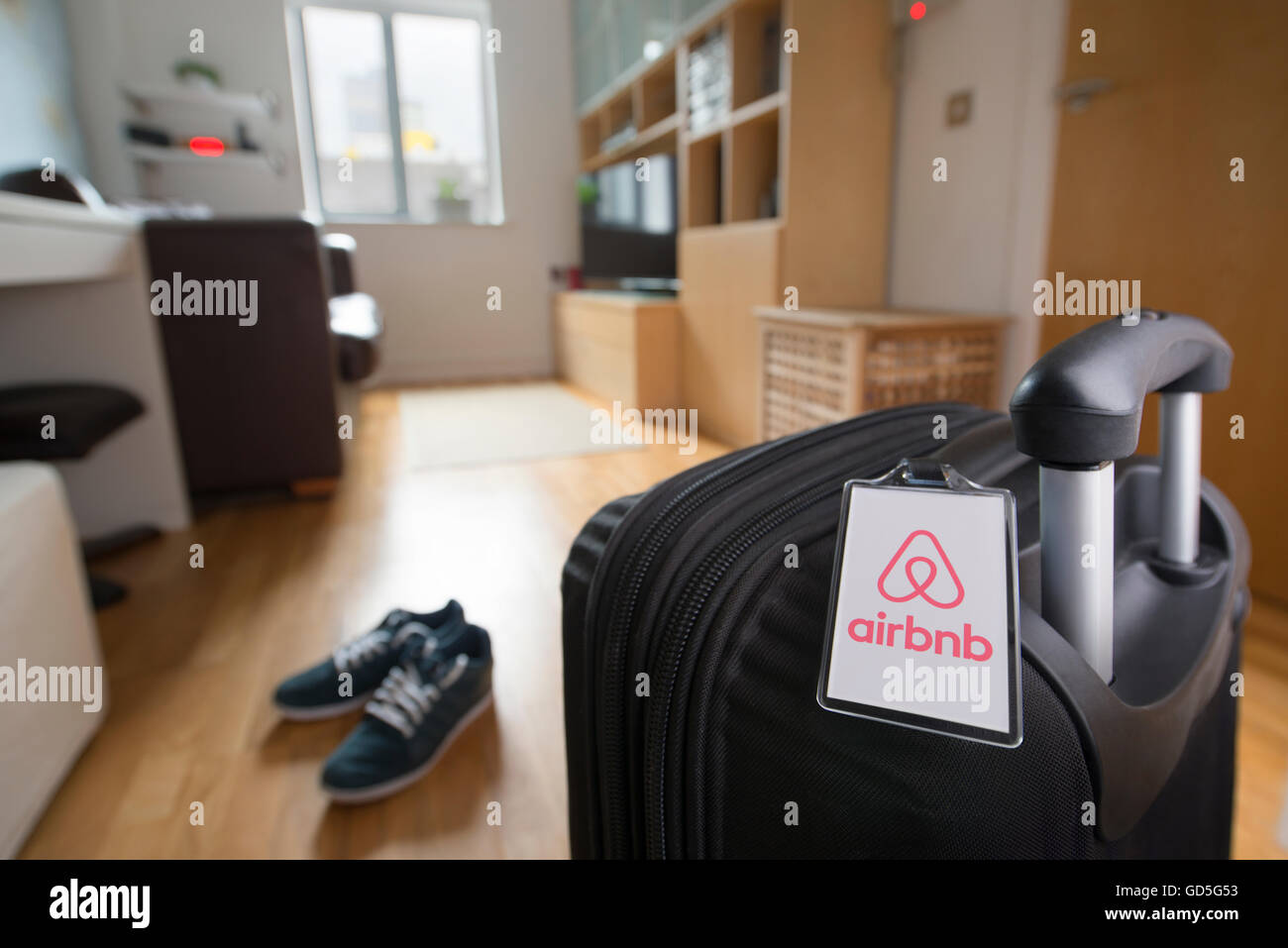 Una maleta con una etiqueta de equipaje marca Airbnb se asienta en un apartamento para alquilar mediante el mercado en línea (sólo para uso editorial). Foto de stock
