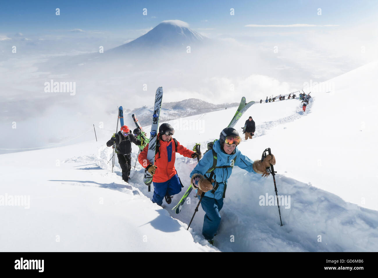 Con el Monte Yotei en el fondo, un grupo de esquiadores de travesía, dirigido por una mujer, son trekking a la cumbre del monte Annupuri, cerca de la estación de esquí de Niseko unida en la isla japonesa de Hokkaido. Los esquís llevan son grandes y amplias permitiendo el invierno en Foto de stock