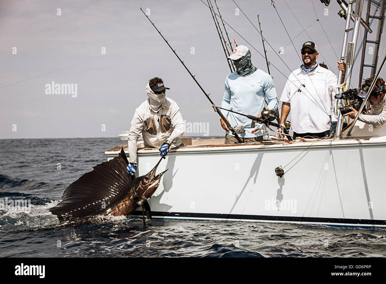 Un grupo de pescadores traen una vela junto a la embarcación. Foto de stock