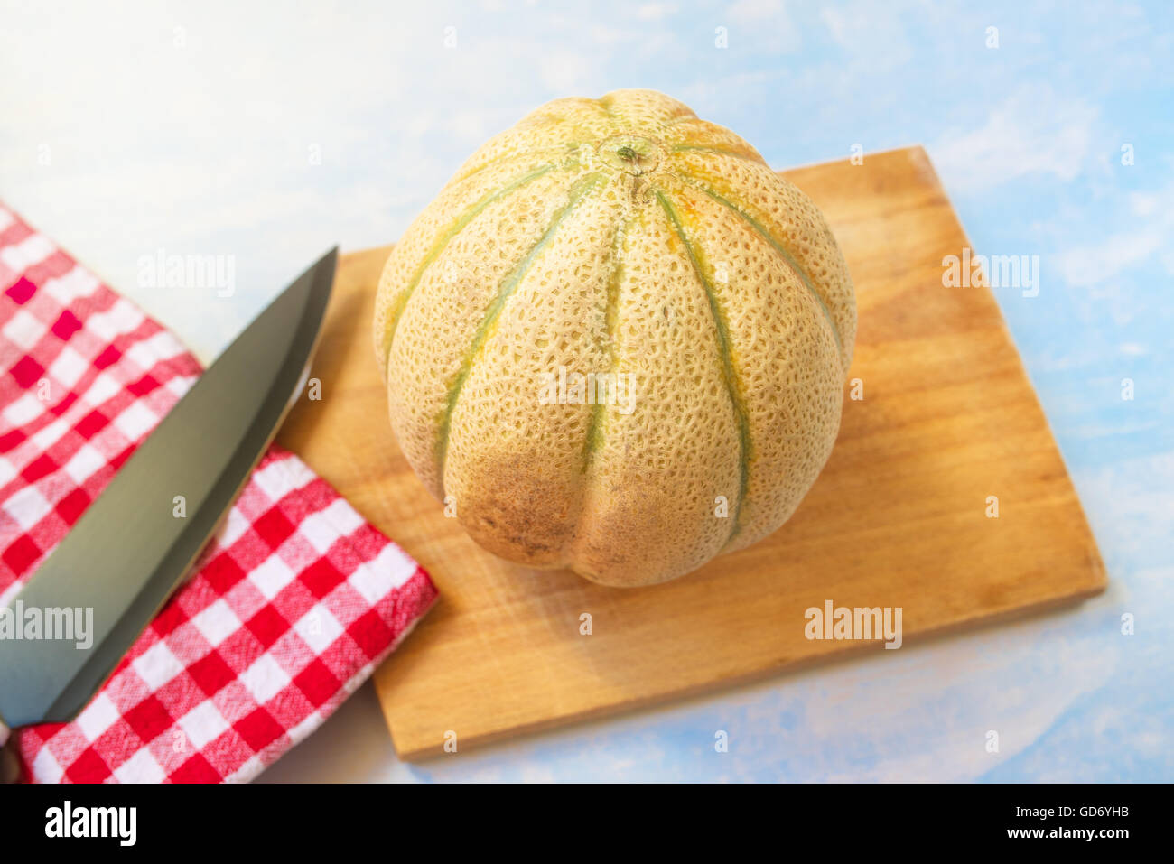 Melón y cuchillo de cocina sobre mesa de madera rústica, fruta entera a bordo, el enfoque selectivo Foto de stock