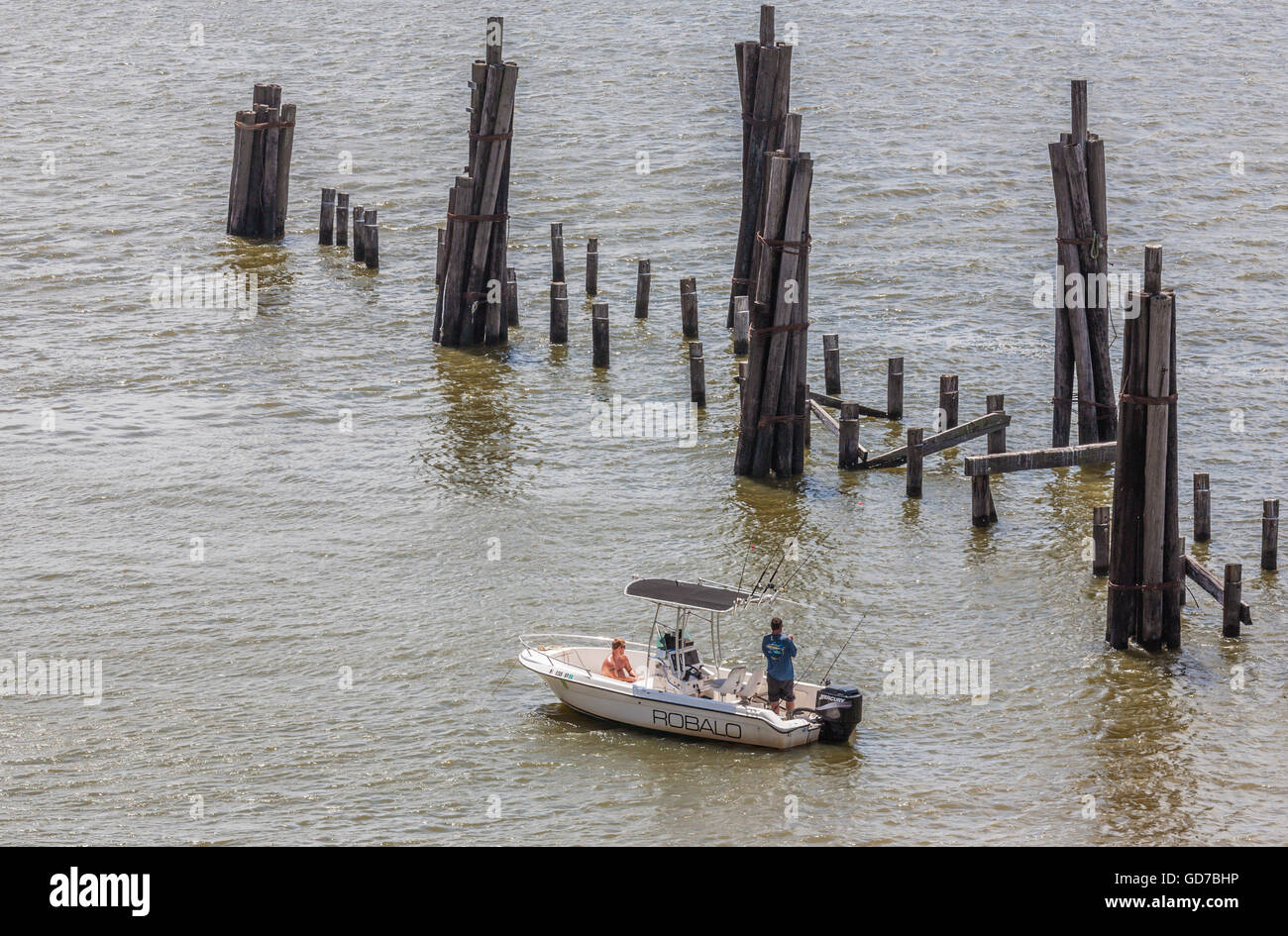 Hombres pescando desde un bote cerca de los restos del muelle de pesca de madera destruido por un huracán en Biloxi, Mississippi Foto de stock