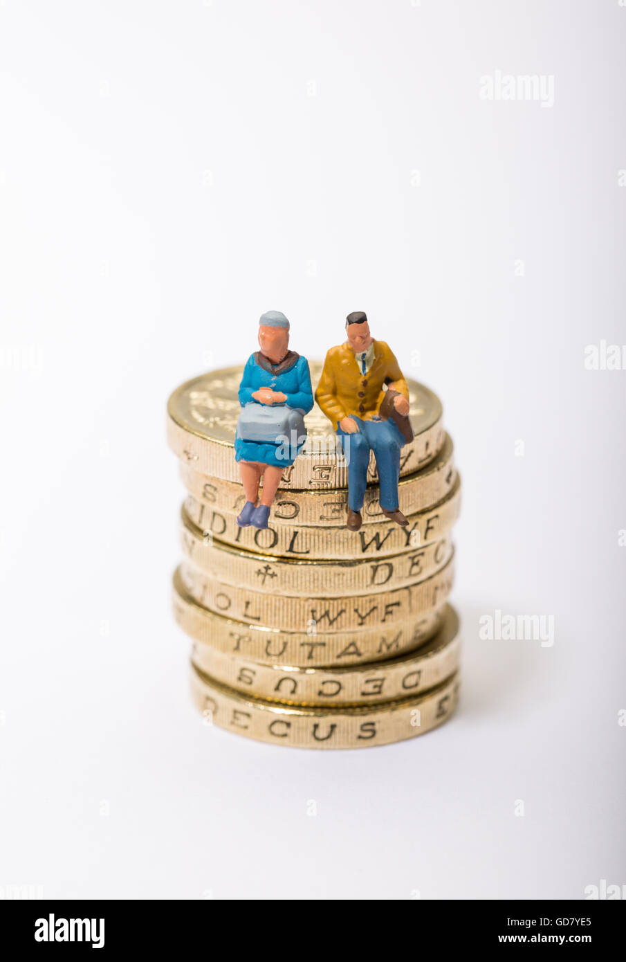 Concepto de imagen dos pensionistas sentado sobre un montón de monedas de libra Foto de stock