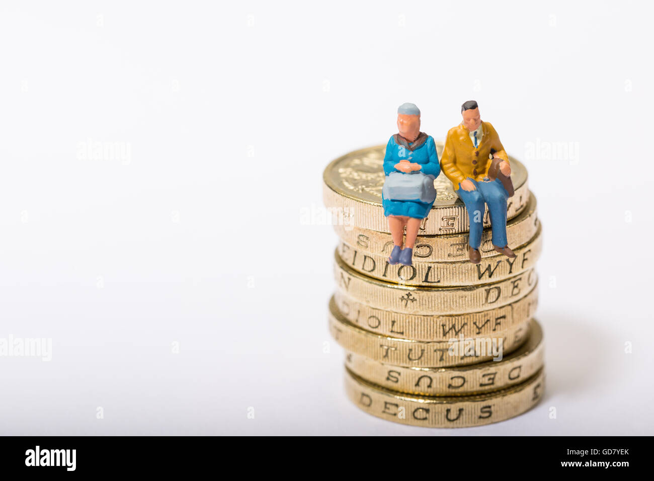 Concepto de imagen dos pensionistas sentado sobre un montón de monedas de libra Foto de stock