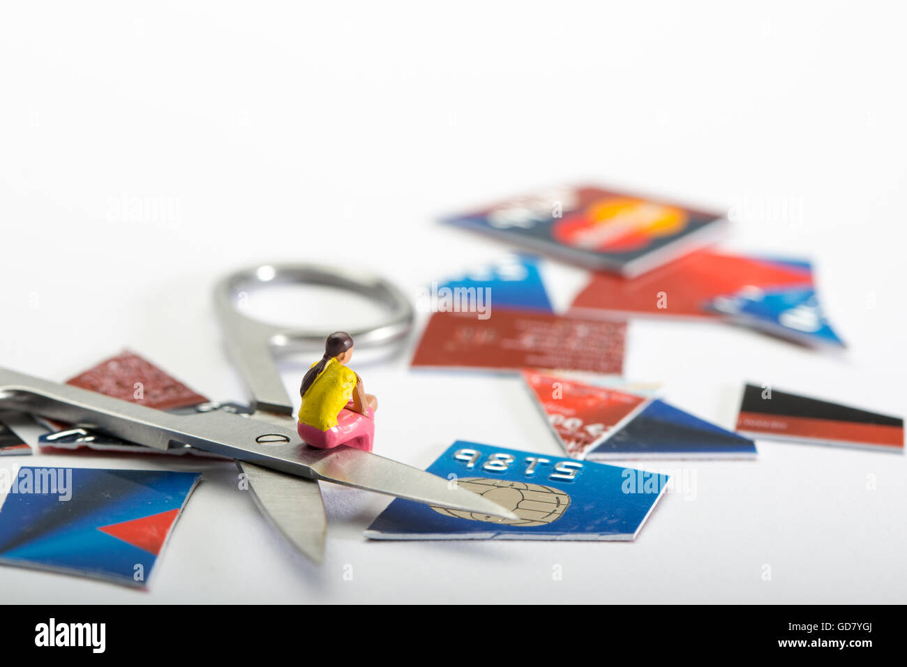 Tarjeta de crédito concepto depart. de la imagen de una figura femenina se sentó con un corte de tarjeta de crédito y un par de tijeras Foto de stock