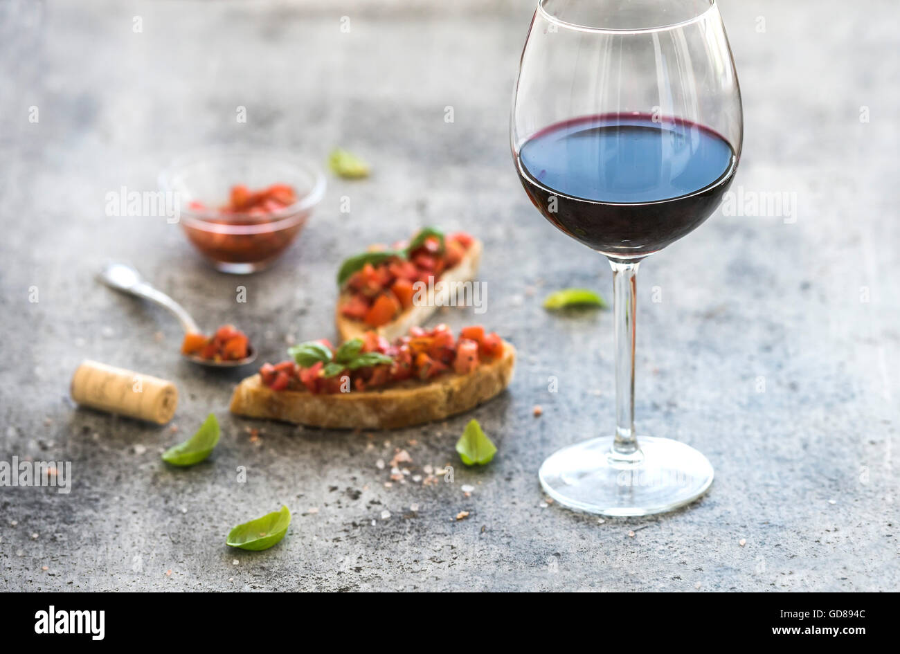 Copa de vino tinto y canapés con tomate y albahaca, el enfoque selectivo, composición horizontal Foto de stock