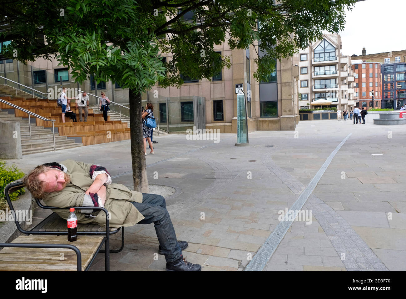Aparentemente, un hombre sin hogar duerme en un banco de Londres con una botella de Coca-Cola en el banquillo junto a él Foto de stock
