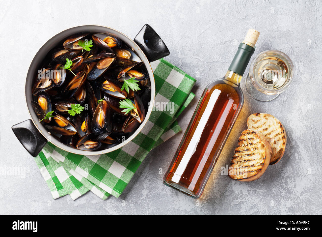 Mejillones en olla de cobre y vino blanco sobre la mesa de piedra. Vista superior Foto de stock