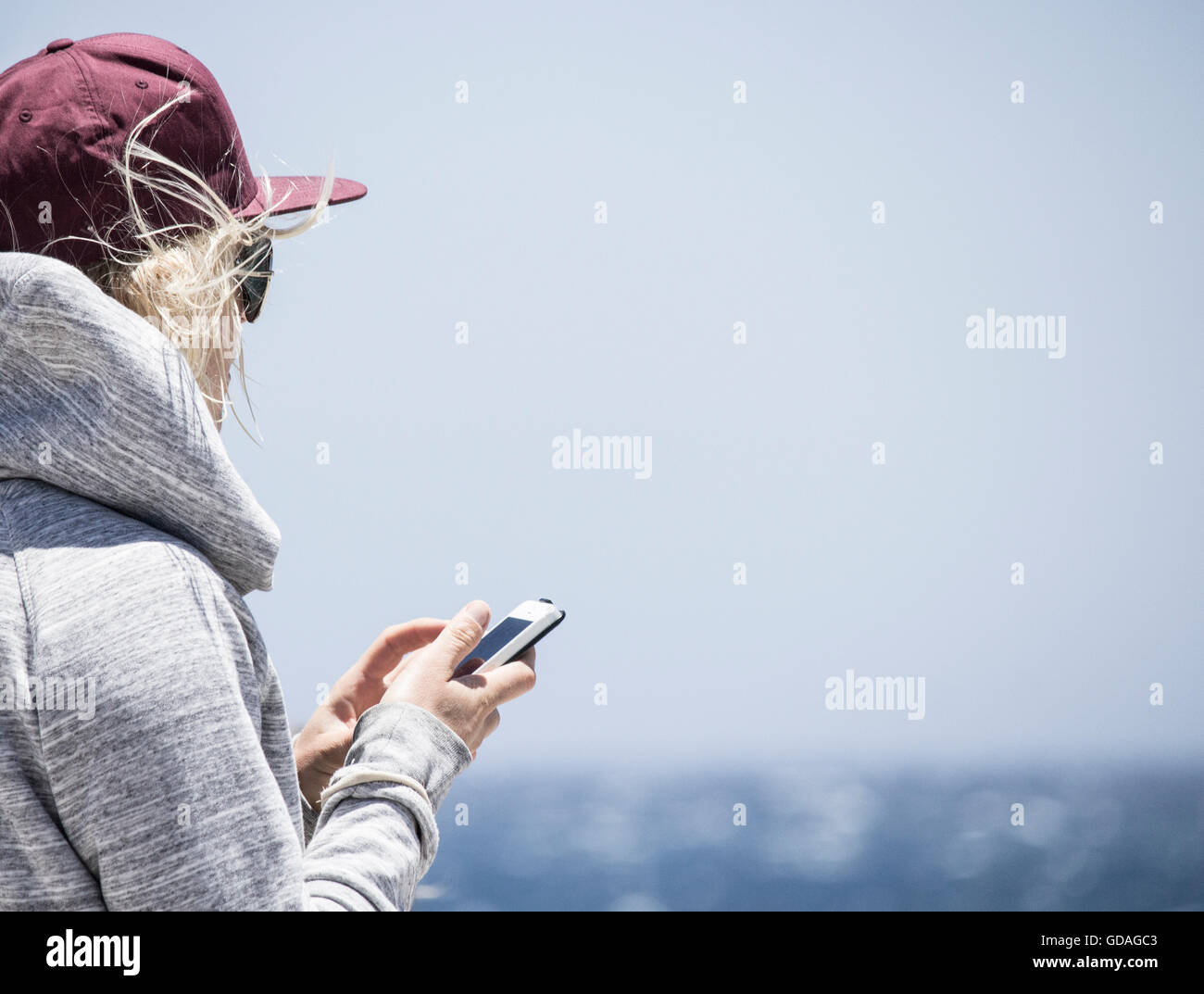 Surfer femenina a través de teléfono móvil en la playa Foto de stock