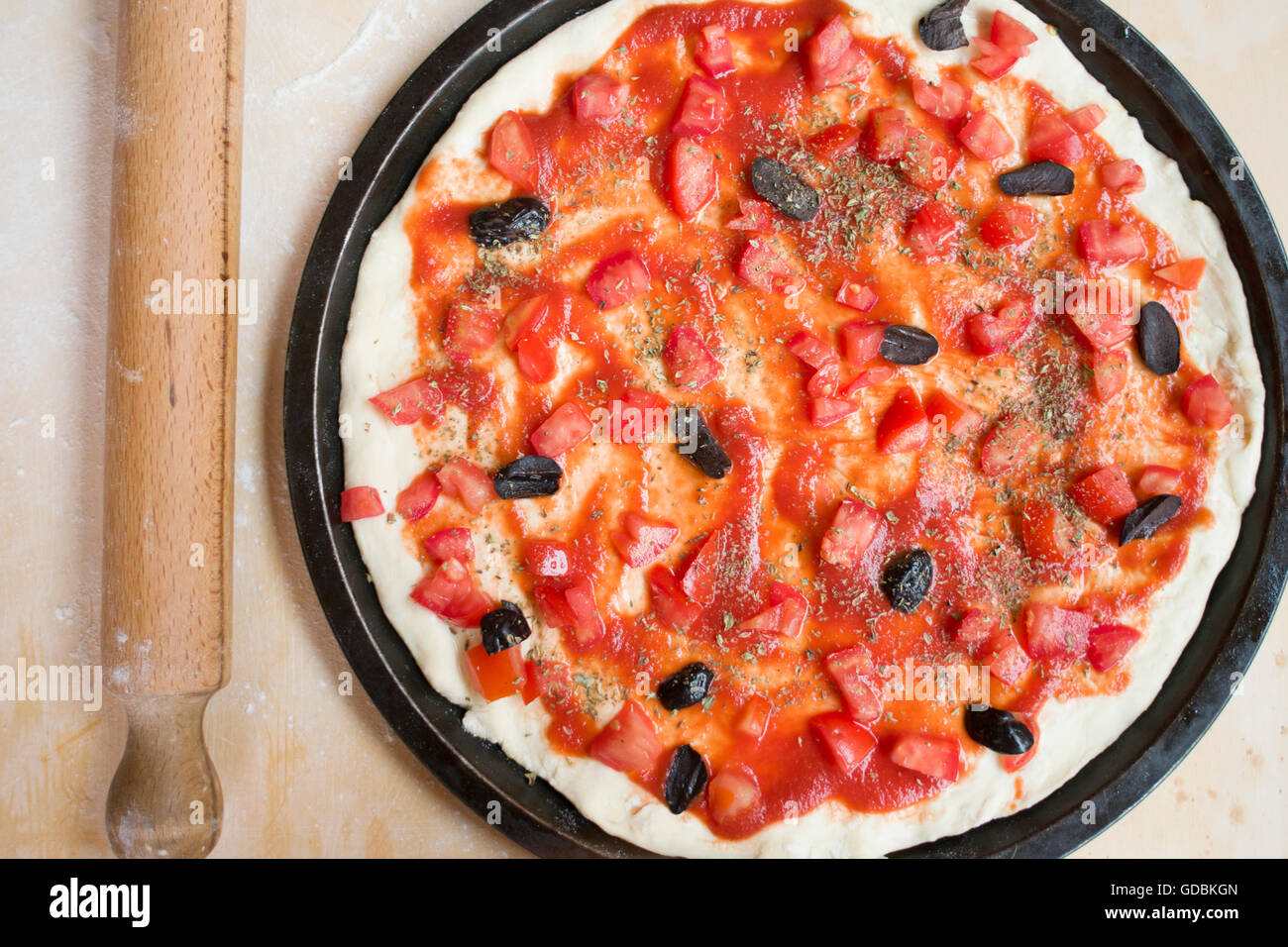 Sentar planas de pizza con tomate fresco y aceitunas negras con cerca de un rodillo Foto de stock