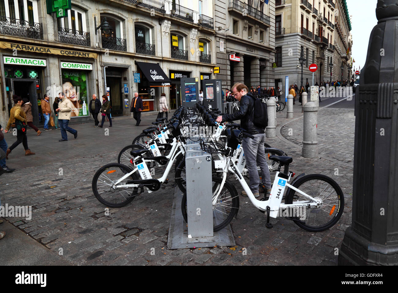 Hombre BiciMAD alquilando una bicicleta eléctrica en una estación de acoplamiento en la Plaza Puerta del Sol, Madrid, España Foto de stock