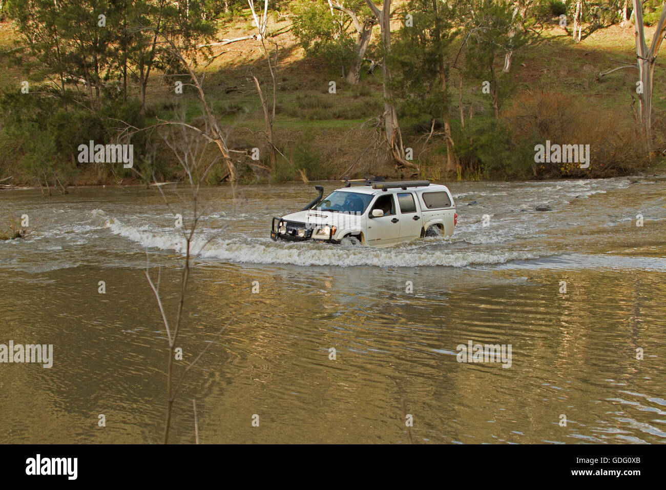 Vehículo de tracción en las cuatro ruedas crear ola de arco de agua tapado blanco haciendo peligroso cruce del río inundado en NSW.Australia Foto de stock