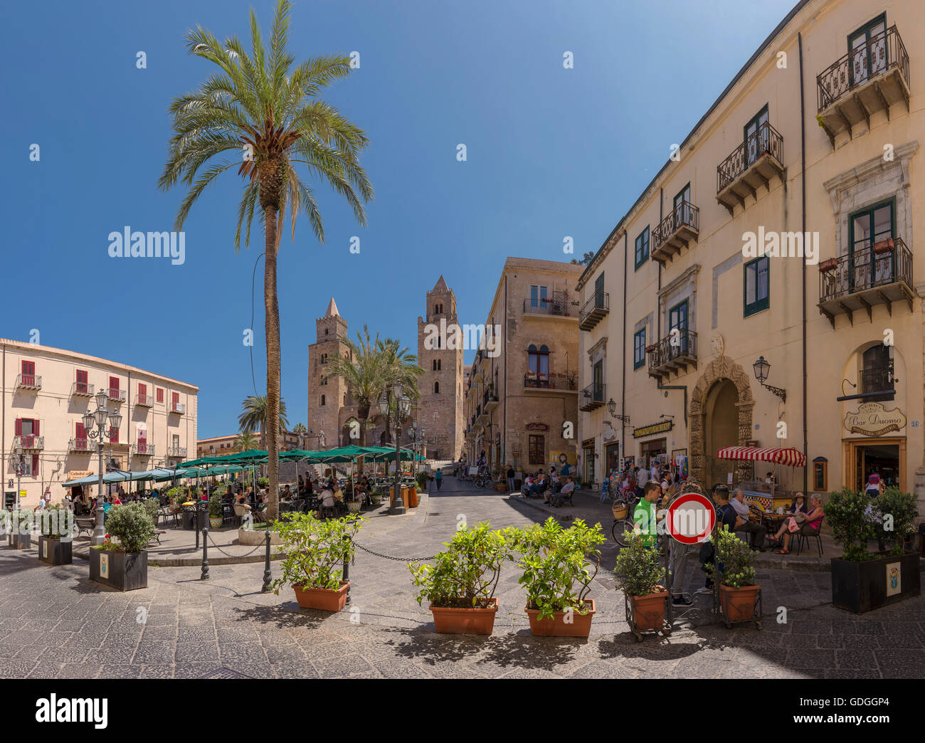 Plaza con cafés al aire libre, sombrillas y palmeras,Catedral de Cefalu Foto de stock