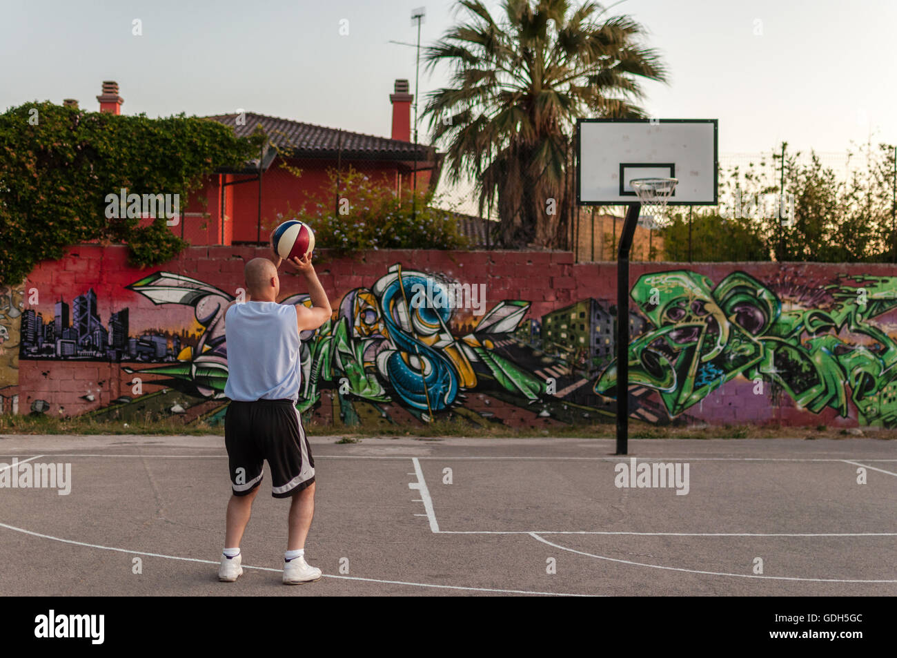 El jugador de baloncesto en el patio de recreo de la ciudad al atardecer Foto de stock