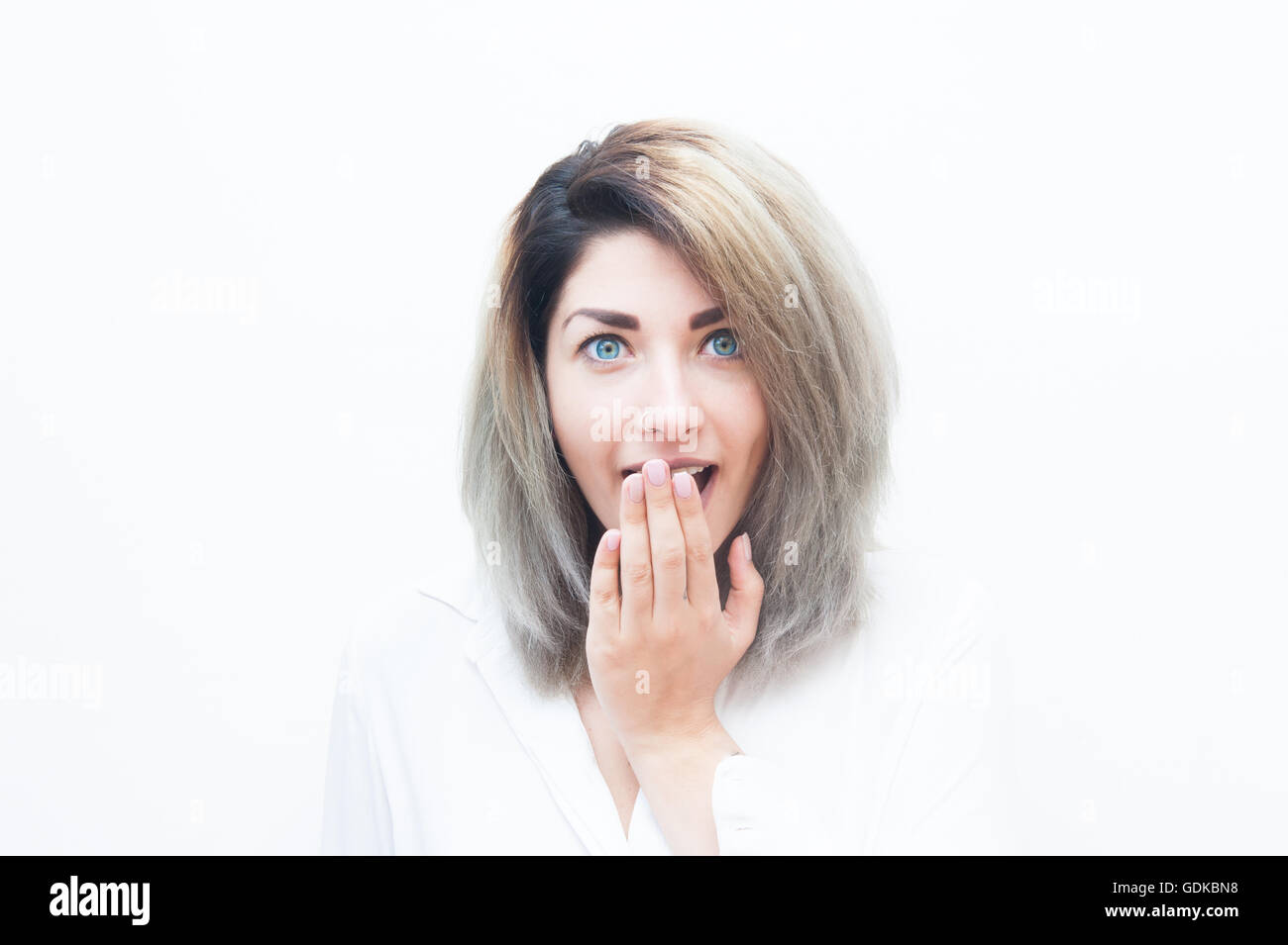Joven mujer rubia de ojos azules de expresión asombrada aislado en blanco vertical Foto de stock
