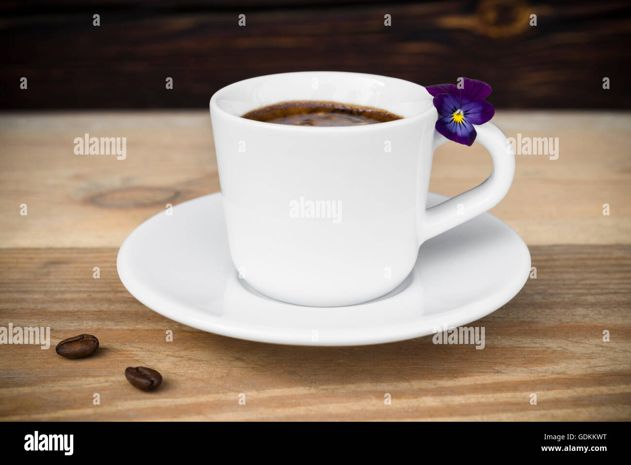 Taza de café espresso con granos de café y las flores dispuestas en la vieja mesa de madera rústica Foto de stock