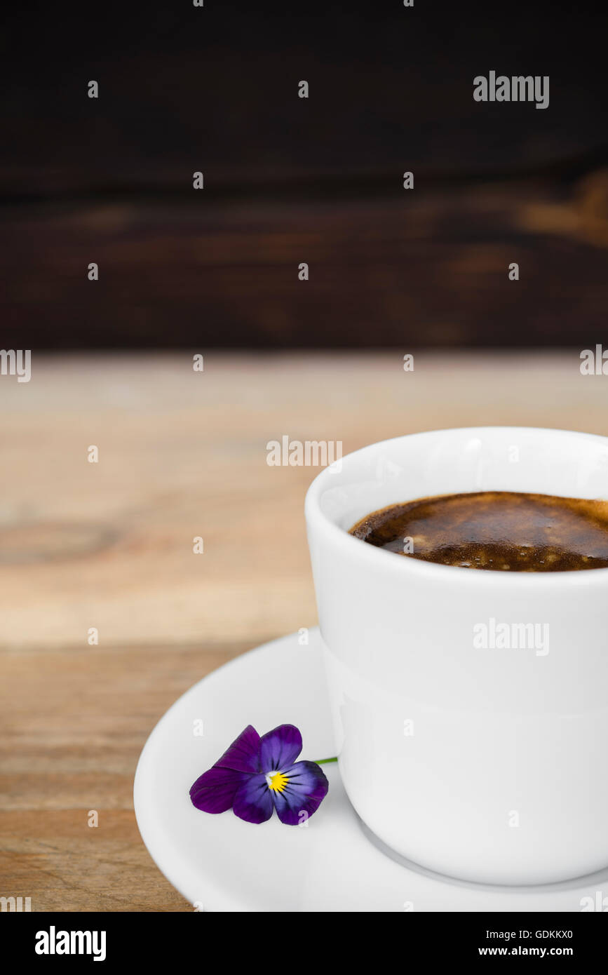 Taza de café espresso con flores dispuestas en la vieja mesa de madera rústica Foto de stock
