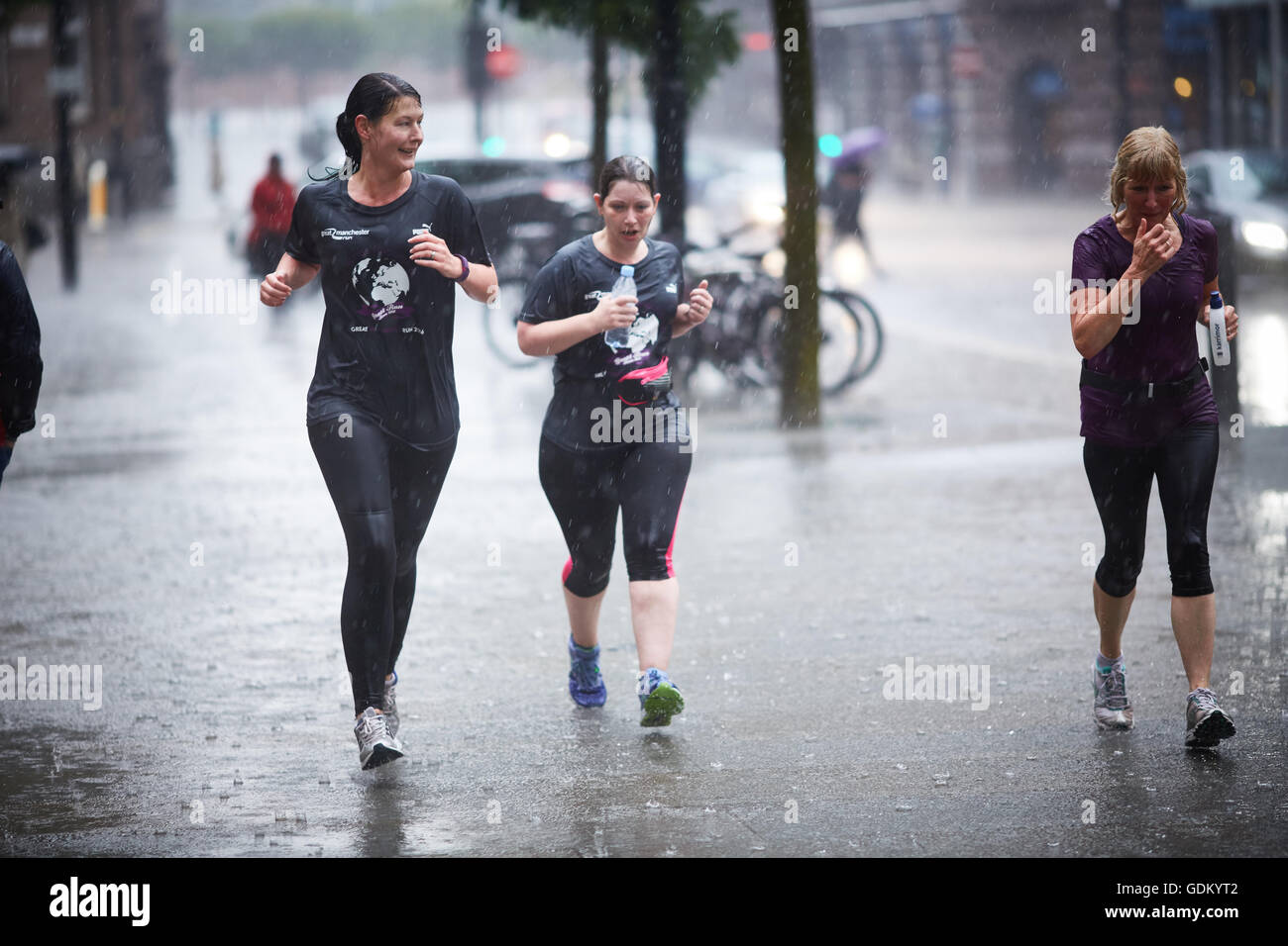 Las fuertes lluvias en el centro de la ciudad de Manchester que llueven pour húmedo empapado en remojo a través de un paraguas de rebote de pavimento de piso spay mi Foto de stock