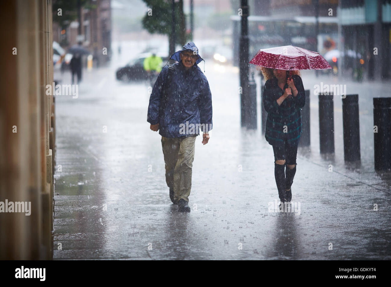 Las fuertes lluvias en el centro de la ciudad de Manchester que llueven pour húmedo empapado en remojo a través de un paraguas de rebote de pavimento de piso spay mi Foto de stock